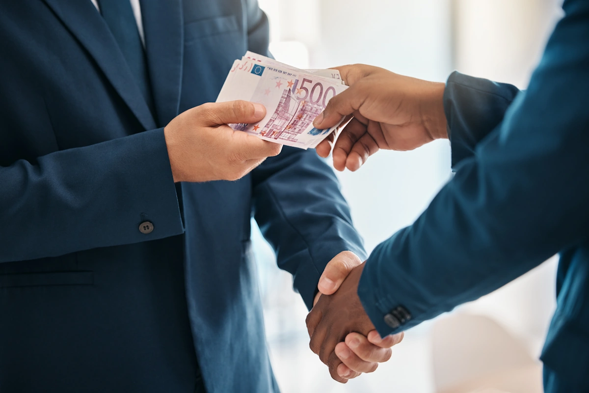 Un homme qui donne de l'argent à un autre en lui tenant la main