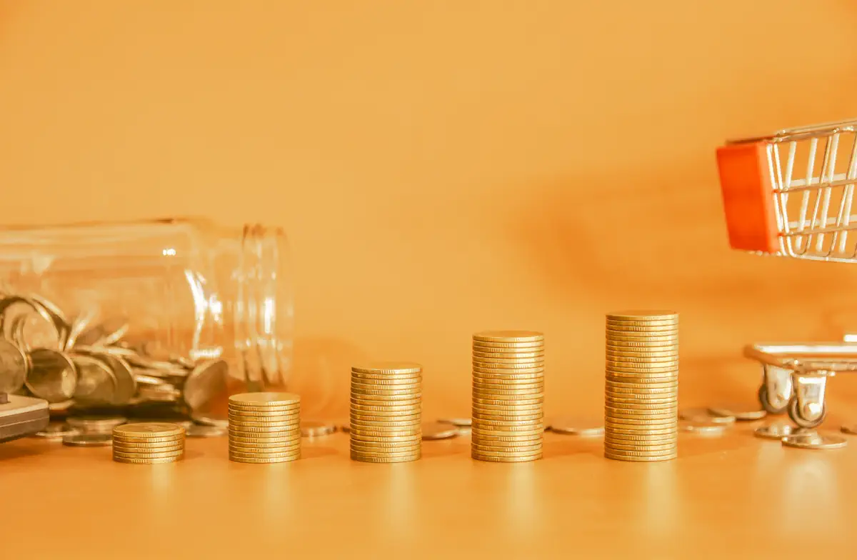 Des piles de monnaies près d'un bocal en verre et un mini quadi