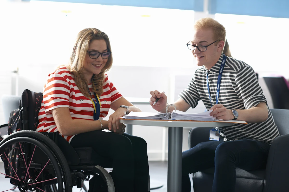 Une femme en fauteuil roulant qui discute avec une autre femme autour d'une femme