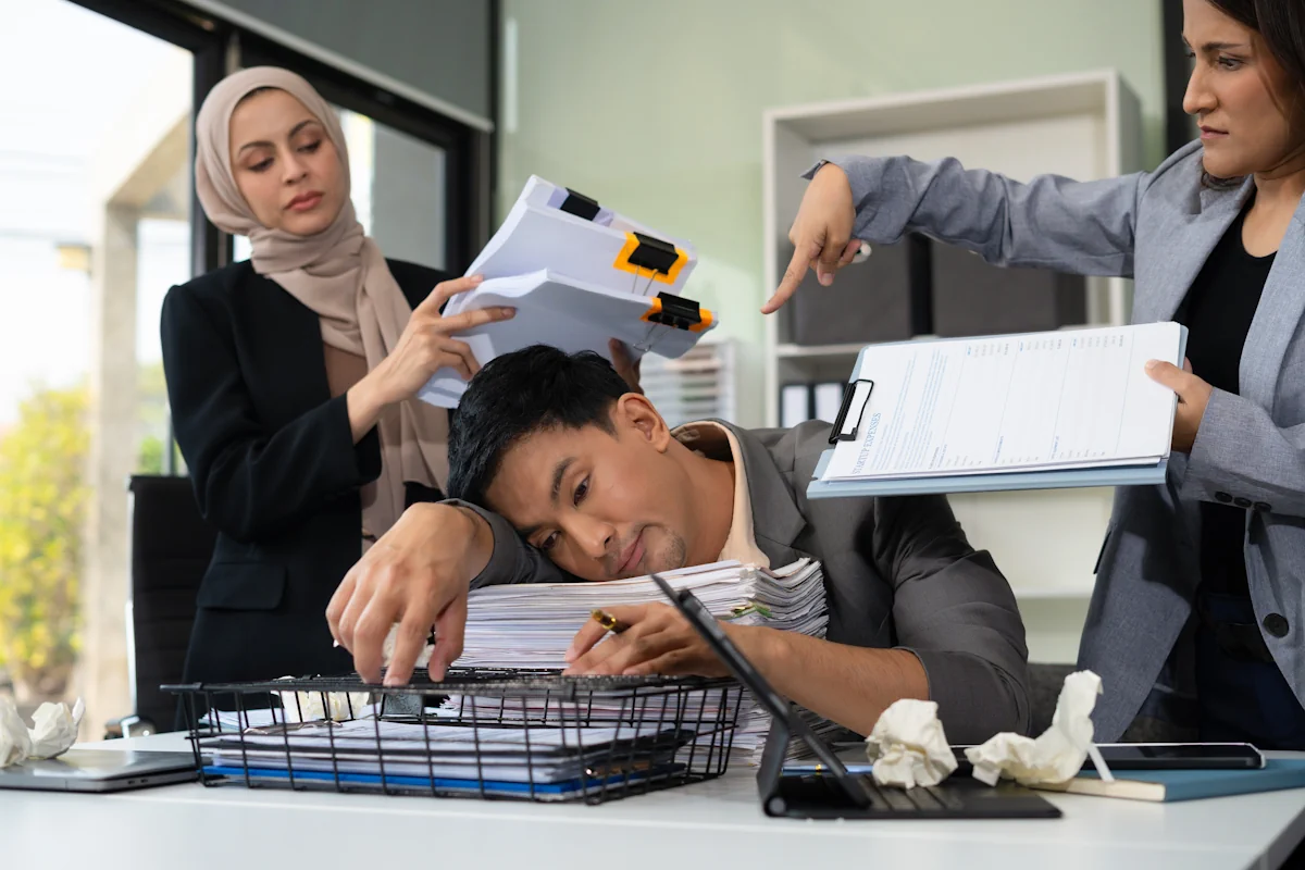 Un homme sous l'eau des dossiers déposés par d'autres personnes sur son bureau