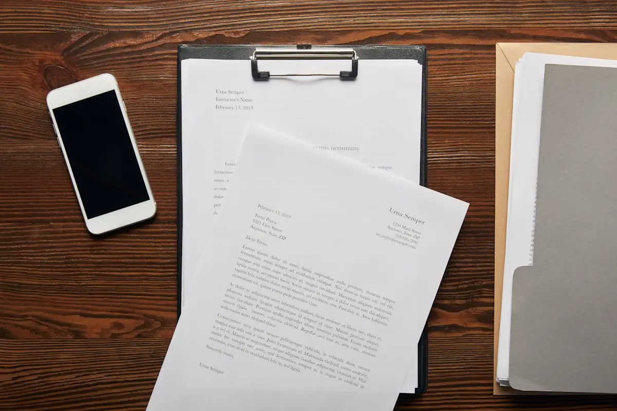 Un smartphone et des documents posés sur une table en bois